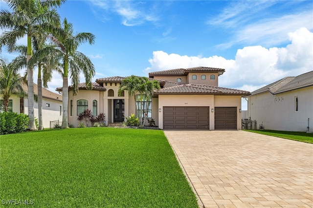 mediterranean / spanish-style house with decorative driveway, a tile roof, stucco siding, a garage, and a front lawn