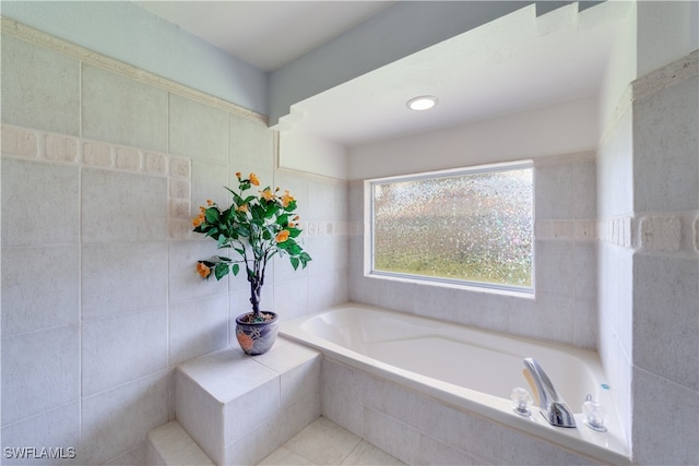 bathroom with tile walls, tiled tub, and tile patterned floors