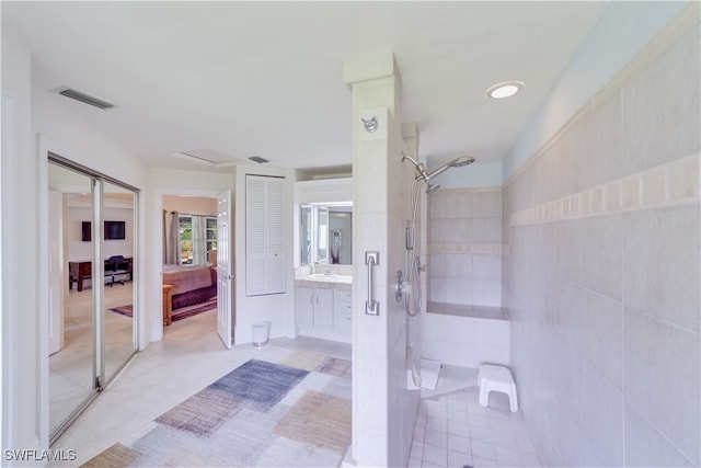 bathroom featuring vanity, tile patterned flooring, and tiled shower