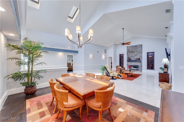 dining area featuring ceiling fan with notable chandelier, a stone fireplace, lofted ceiling, and wood-type flooring