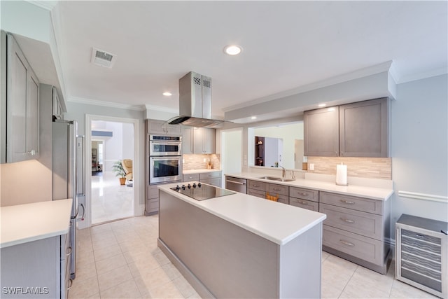 kitchen featuring sink, tasteful backsplash, island range hood, beverage cooler, and appliances with stainless steel finishes