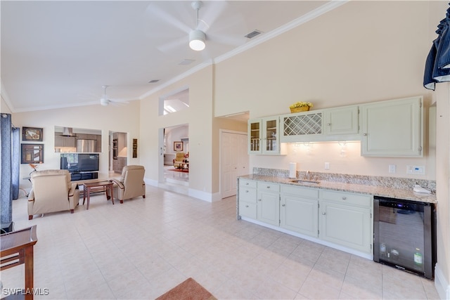 kitchen with ornamental molding, sink, ceiling fan, and light stone counters