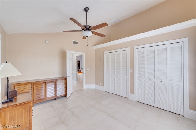 bedroom with ceiling fan, two closets, and high vaulted ceiling