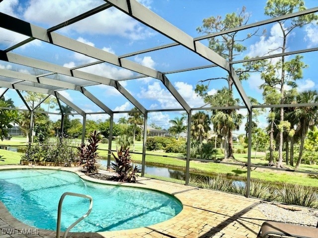 view of pool with a water view, a patio area, and glass enclosure