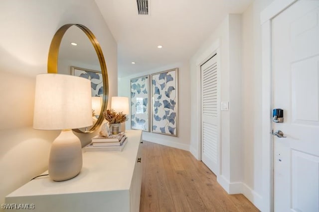 hallway featuring recessed lighting, visible vents, baseboards, and light wood finished floors