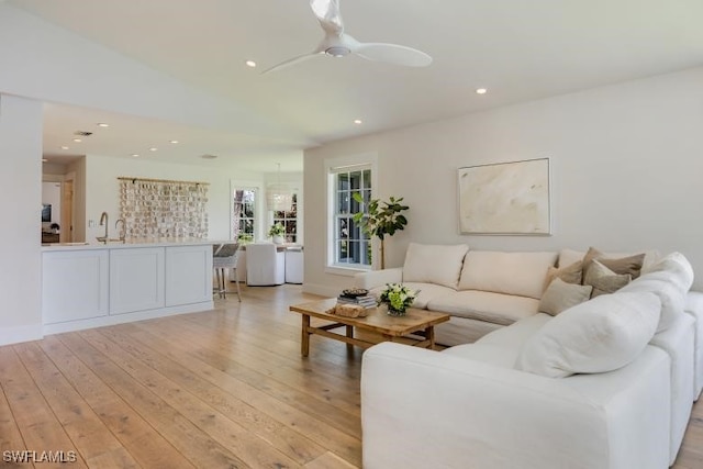 living room with lofted ceiling, ceiling fan, and light hardwood / wood-style floors