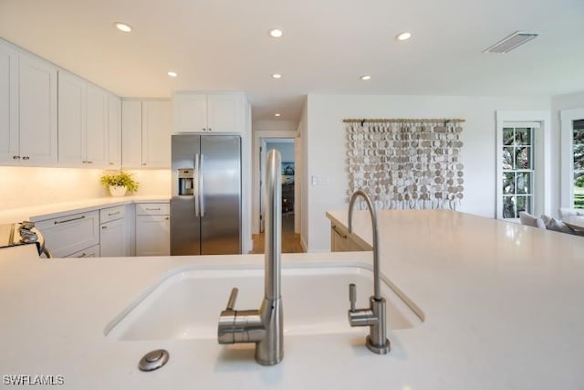 kitchen with white cabinets, sink, and stainless steel refrigerator with ice dispenser