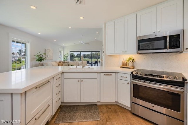 kitchen with light wood-style flooring, stainless steel appliances, light countertops, and a sink