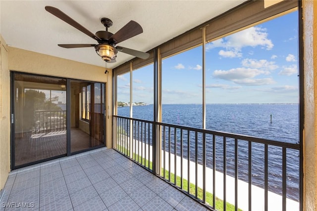 unfurnished sunroom with ceiling fan, a water view, and a healthy amount of sunlight