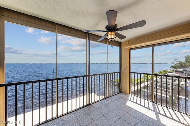 unfurnished sunroom with a water view and ceiling fan