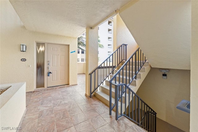 interior space featuring stairway, floor to ceiling windows, a textured ceiling, and a textured wall