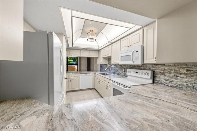 kitchen with white cabinetry, sink, light stone countertops, backsplash, and white appliances