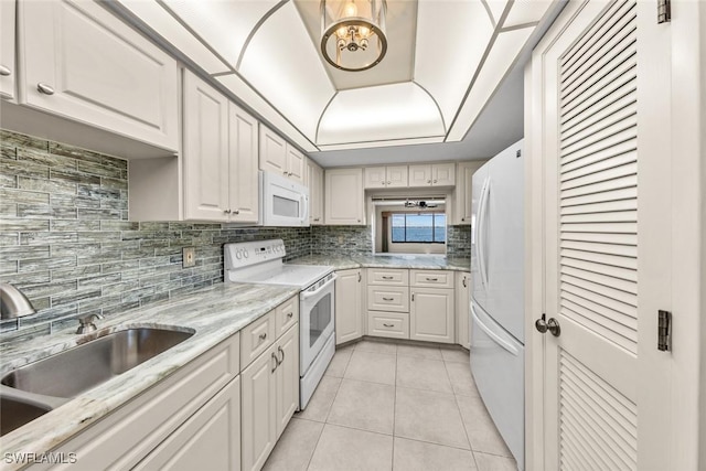 kitchen with light tile patterned floors, decorative backsplash, white cabinetry, a sink, and white appliances