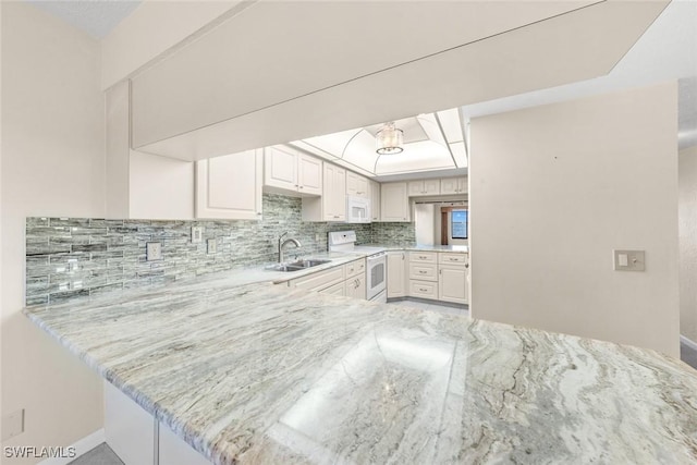 kitchen featuring kitchen peninsula, decorative backsplash, white appliances, sink, and white cabinetry