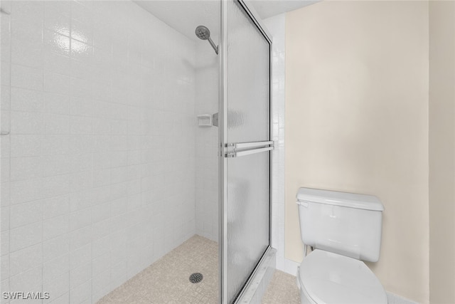 bathroom with a shower with door and toilet