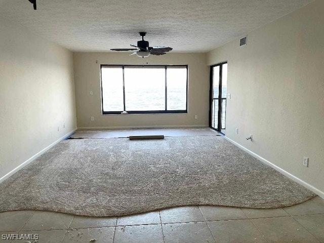 carpeted empty room featuring visible vents, ceiling fan, a textured ceiling, and baseboards