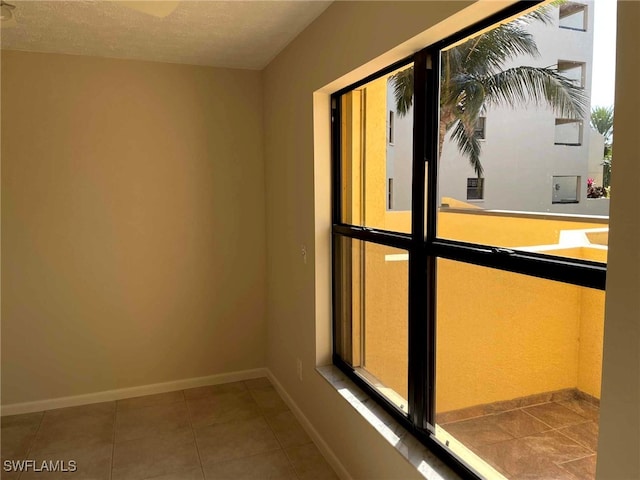 interior space with baseboards, a textured ceiling, and tile patterned floors