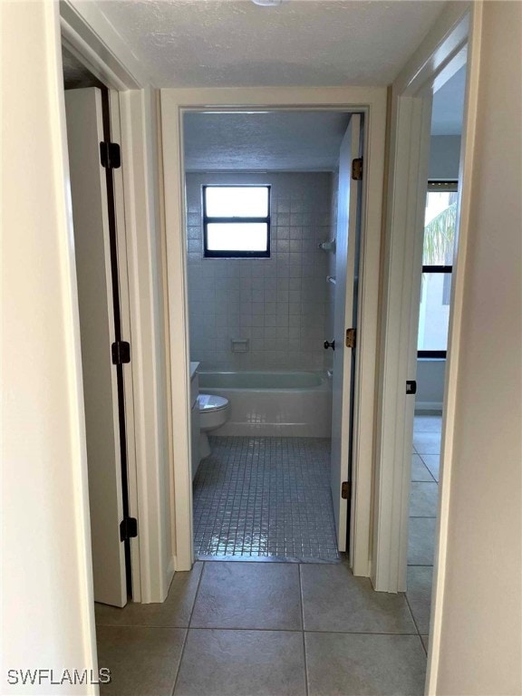 hallway featuring light tile patterned flooring and a textured ceiling