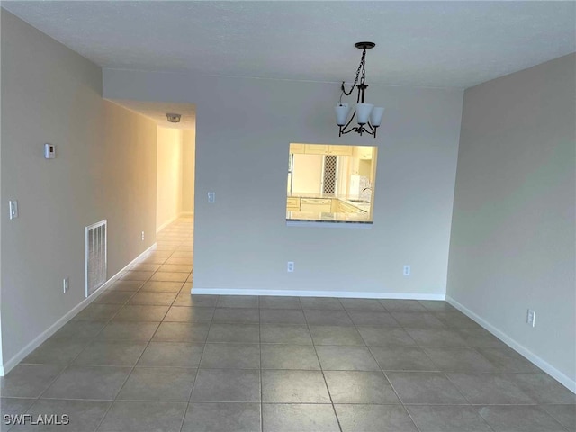 unfurnished dining area featuring baseboards, dark tile patterned floors, visible vents, and an inviting chandelier