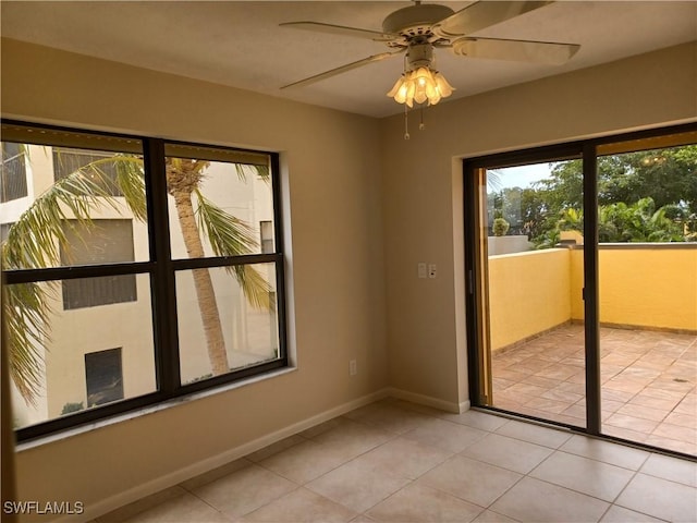 empty room with light tile patterned flooring, a ceiling fan, and baseboards