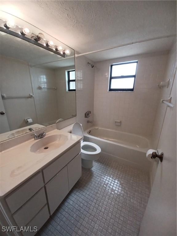 full bathroom with a textured ceiling, toilet, vanity, bathing tub / shower combination, and tile patterned floors