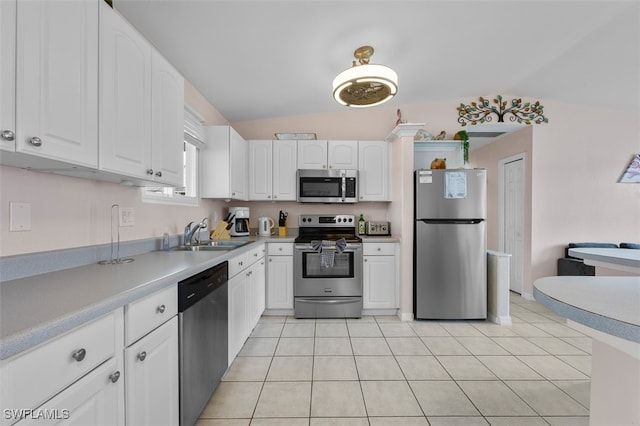 kitchen with white cabinets, vaulted ceiling, sink, appliances with stainless steel finishes, and light tile patterned flooring