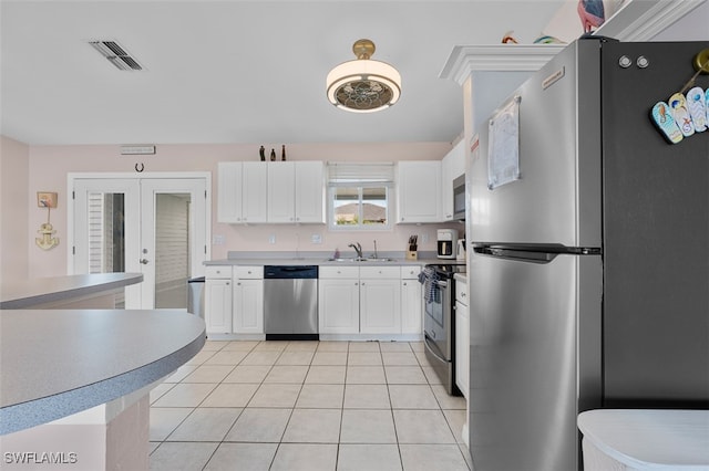 kitchen with appliances with stainless steel finishes, light tile patterned flooring, sink, and white cabinets