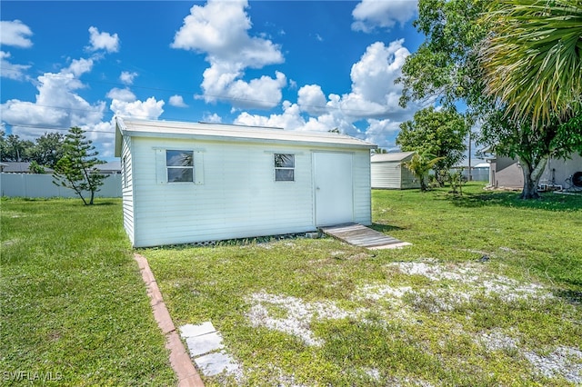 rear view of property with an outdoor structure and a yard