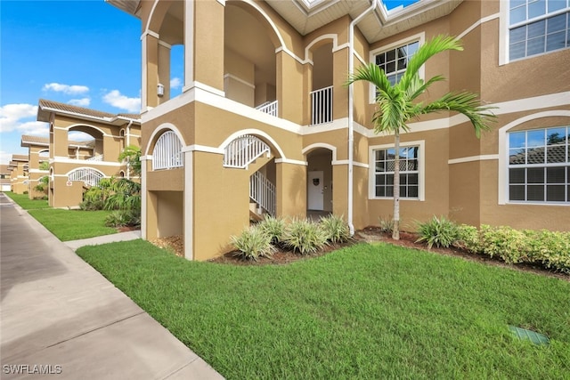 view of front of house featuring a balcony and a front yard