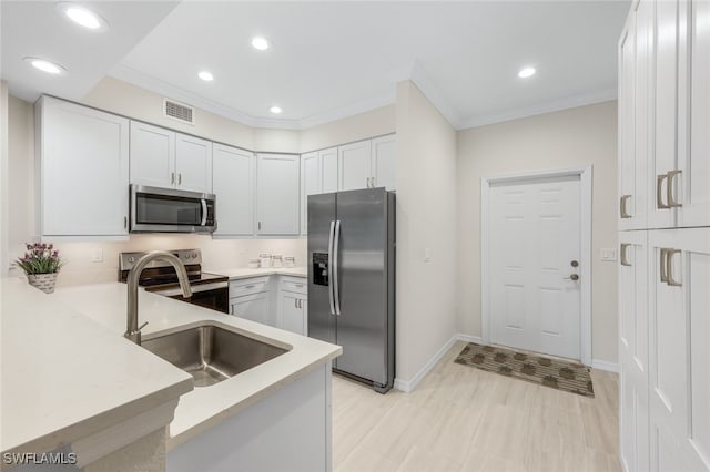 kitchen with crown molding, stainless steel appliances, sink, light wood-type flooring, and white cabinets