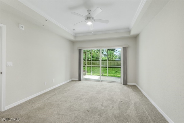 unfurnished room with light carpet, crown molding, a tray ceiling, and ceiling fan