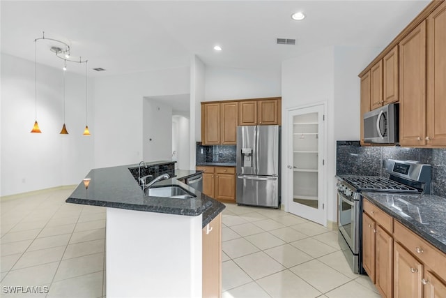 kitchen featuring backsplash, sink, light tile patterned floors, an island with sink, and stainless steel appliances