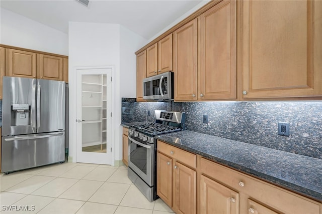 kitchen featuring tasteful backsplash, light tile patterned floors, dark stone counters, and appliances with stainless steel finishes