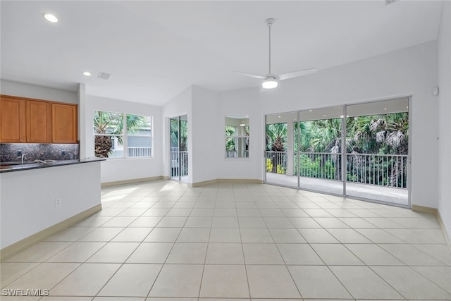 unfurnished living room with ceiling fan, light tile patterned flooring, and lofted ceiling