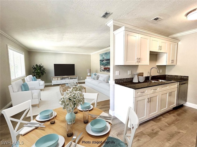 kitchen with ornamental molding, stainless steel dishwasher, white cabinetry, and sink