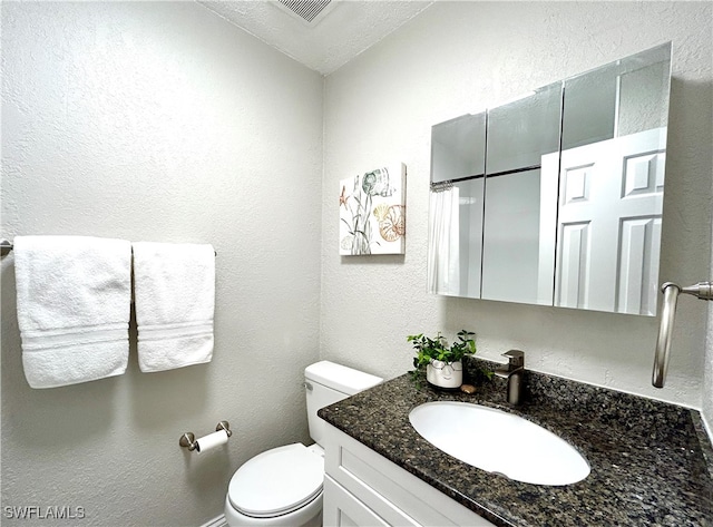 bathroom featuring vanity, toilet, and a textured ceiling