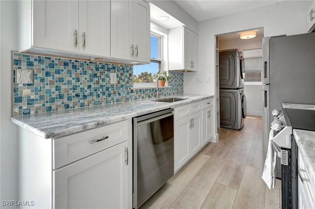 kitchen featuring white cabinets, stove, stainless steel dishwasher, and stacked washer / dryer