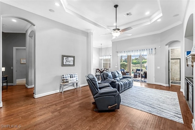 living room featuring ornamental molding, a raised ceiling, hardwood / wood-style floors, and ceiling fan