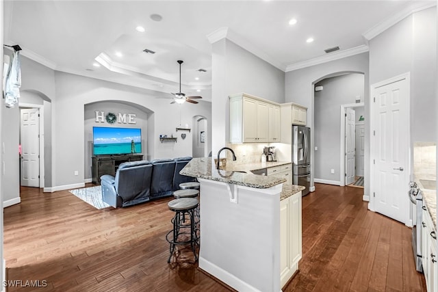 kitchen with wood-type flooring, stainless steel fridge with ice dispenser, crown molding, kitchen peninsula, and ceiling fan