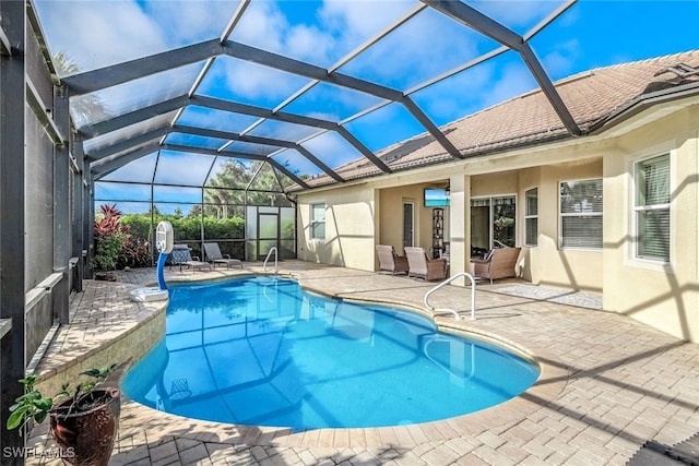 view of pool with glass enclosure and a patio