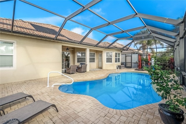 view of swimming pool with ceiling fan, a lanai, and a patio