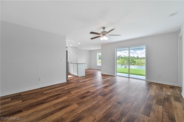 unfurnished living room featuring ceiling fan and dark hardwood / wood-style flooring