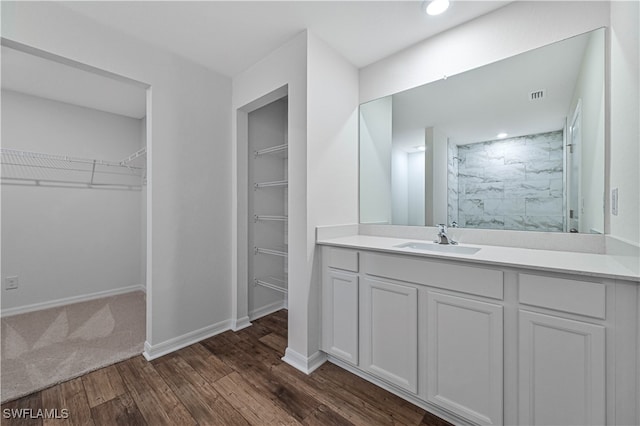 bathroom with tiled shower, vanity, and hardwood / wood-style flooring