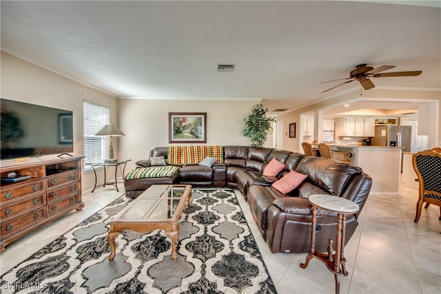 tiled living room with ornamental molding and ceiling fan