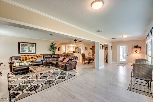 living room featuring light hardwood / wood-style flooring, ceiling fan, and ornamental molding