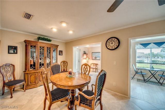 tiled dining space with ceiling fan and crown molding