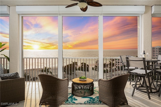 sunroom / solarium featuring a water view and ceiling fan