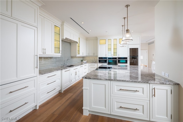 kitchen featuring stainless steel appliances, white cabinetry, dark hardwood / wood-style floors, pendant lighting, and sink