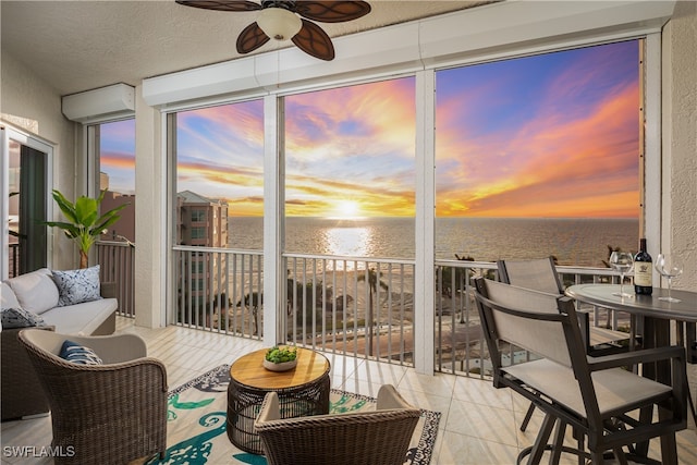 sunroom / solarium featuring a water view and ceiling fan