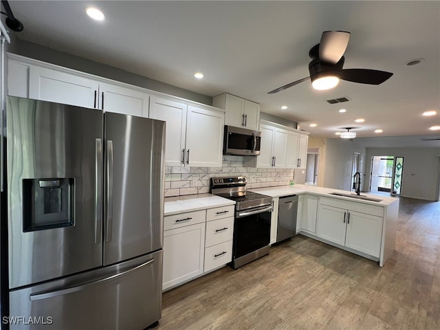 kitchen with sink, appliances with stainless steel finishes, white cabinetry, kitchen peninsula, and light wood-type flooring